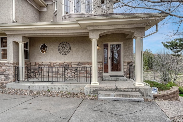 property entrance with a porch, stone siding, and stucco siding