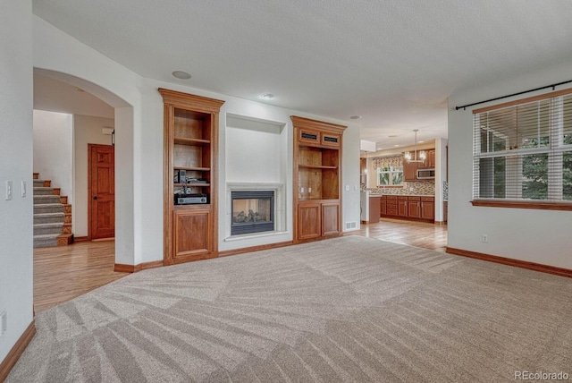 unfurnished living room featuring baseboards, stairs, light carpet, and a fireplace