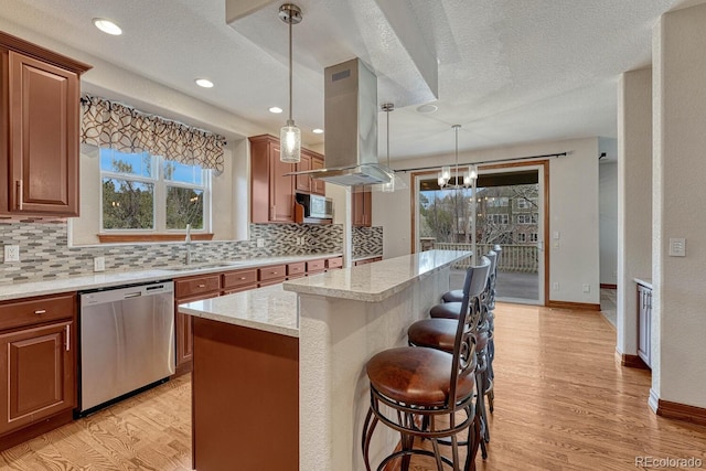 kitchen with appliances with stainless steel finishes, tasteful backsplash, a sink, light wood-type flooring, and a kitchen bar