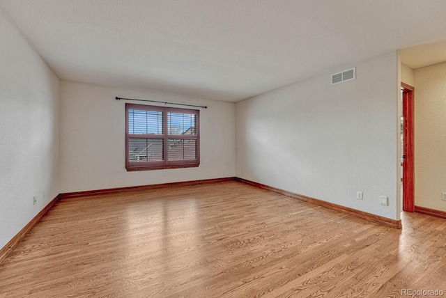 empty room featuring visible vents, baseboards, and light wood-type flooring