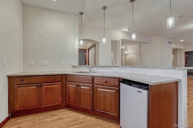 kitchen with a sink, fridge, brown cabinets, and light wood-style flooring