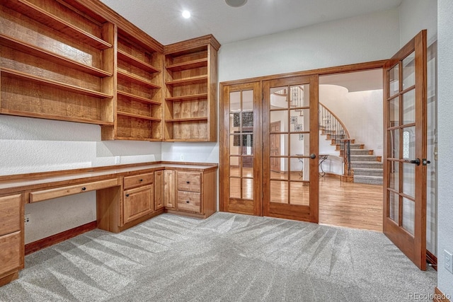 unfurnished office featuring built in desk, light carpet, and french doors