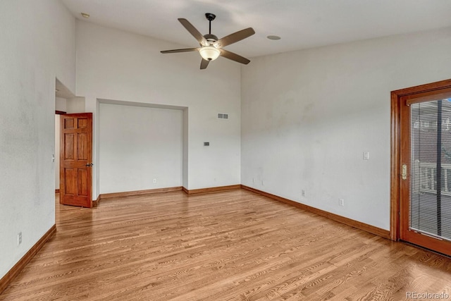 spare room with visible vents, baseboards, high vaulted ceiling, light wood-type flooring, and a ceiling fan