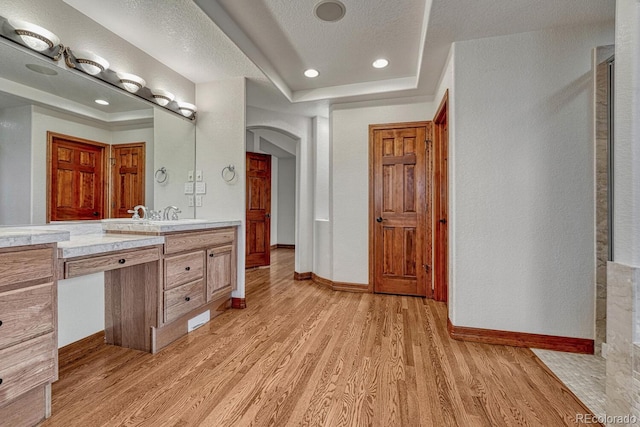 bathroom featuring baseboards, wood finished floors, a raised ceiling, and vanity