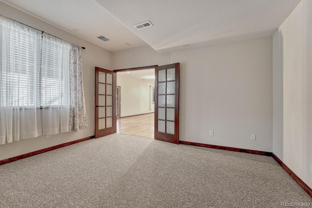 spare room with carpet floors, baseboards, french doors, and visible vents