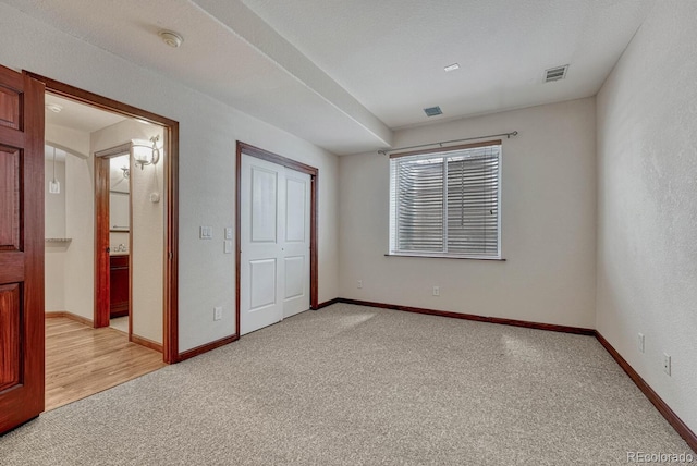 unfurnished bedroom with baseboards, visible vents, a closet, and light colored carpet