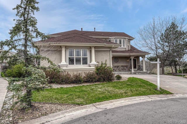 view of front of house featuring roof with shingles, stucco siding, a front yard, concrete driveway, and covered porch