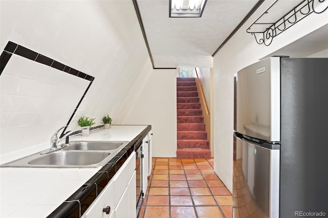 779 High Point Cir, Black Hawk, CO 80422 - kitchen featuring freestanding refrigerator, tile counters, white cabinets, a sink, and arched walkways