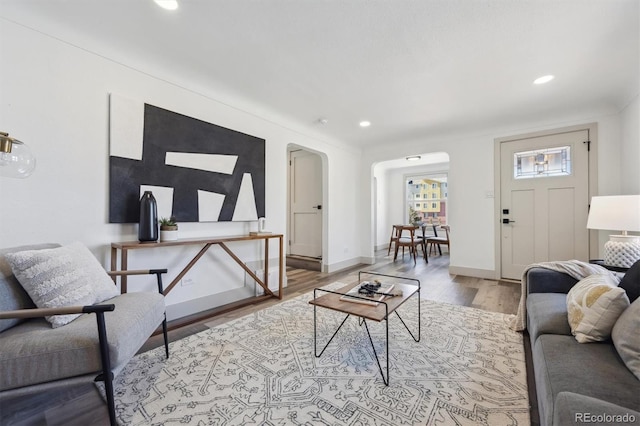 living area with baseboards, arched walkways, wood finished floors, and recessed lighting