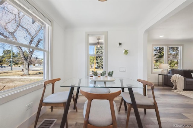 dining room featuring visible vents, arched walkways, and wood finished floors