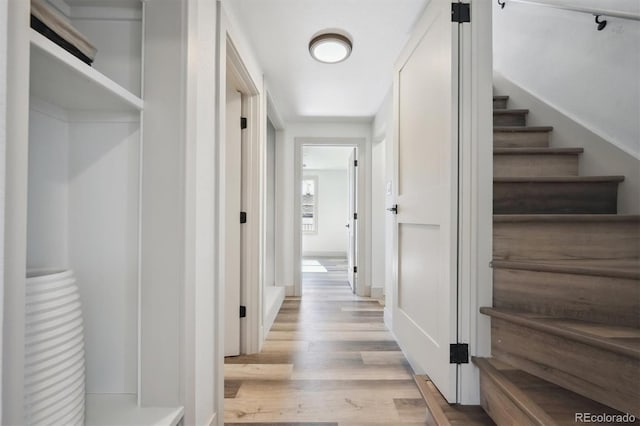 hallway with light wood finished floors and stairway