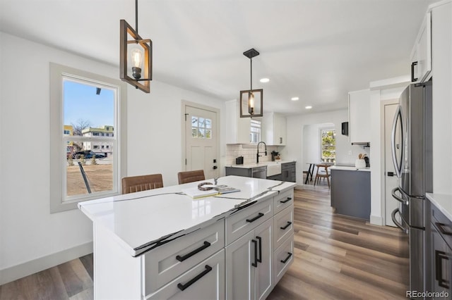 kitchen with tasteful backsplash, freestanding refrigerator, light countertops, and wood finished floors