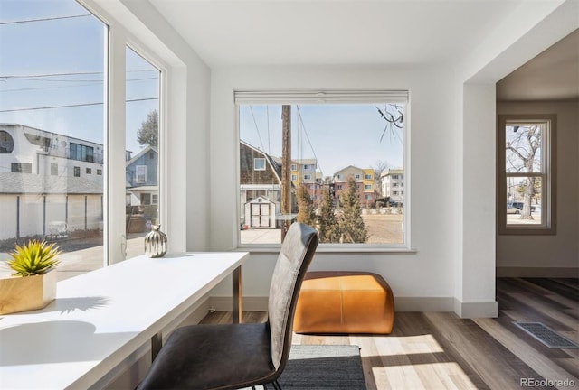 office area featuring a wealth of natural light, visible vents, baseboards, and wood finished floors