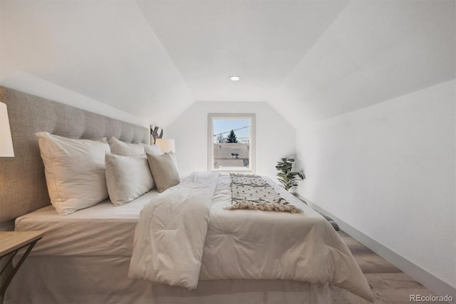 bedroom with lofted ceiling and baseboards