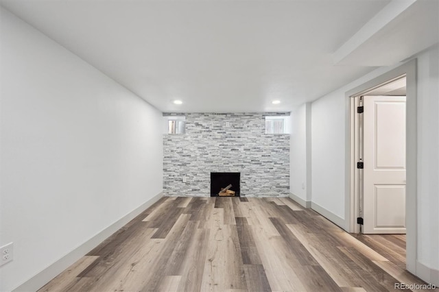 unfurnished living room featuring a fireplace, wood finished floors, and baseboards