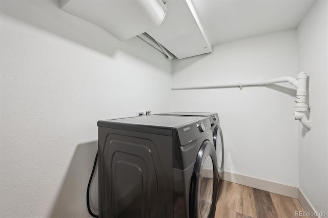 washroom with laundry area, independent washer and dryer, wood finished floors, and baseboards