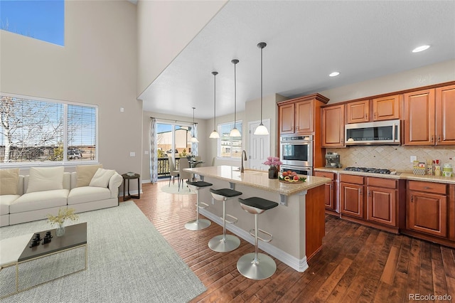 kitchen featuring stainless steel appliances, tasteful backsplash, dark wood-type flooring, and brown cabinetry