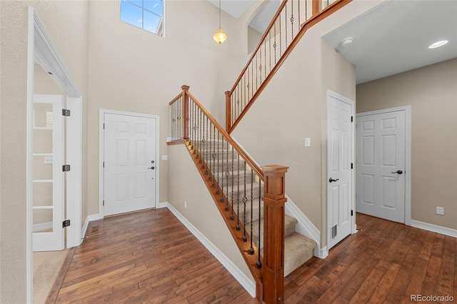 stairs with a high ceiling, baseboards, and hardwood / wood-style flooring