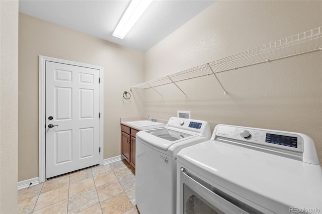 laundry area with washing machine and dryer, cabinet space, baseboards, and a sink