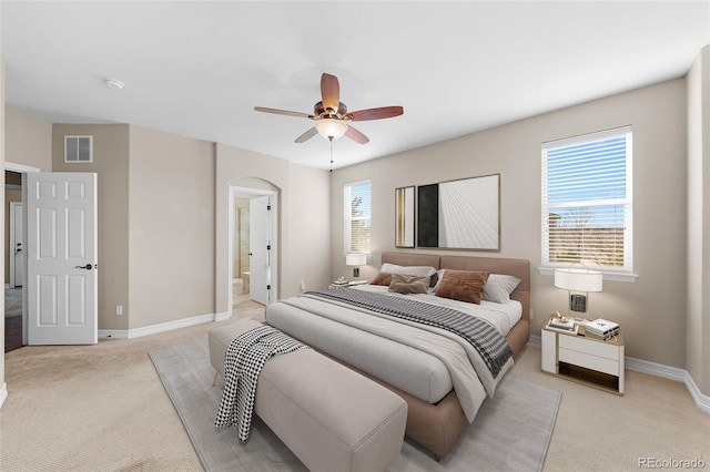 bedroom with visible vents, baseboards, arched walkways, light colored carpet, and connected bathroom