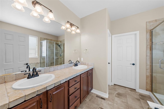 full bathroom with a shower stall, double vanity, visible vents, and a sink