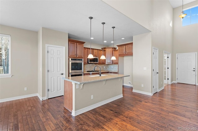 kitchen featuring dark wood finished floors, brown cabinets, appliances with stainless steel finishes, and a sink