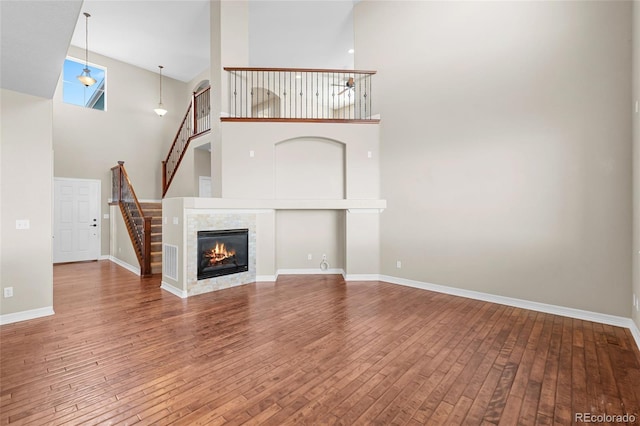 unfurnished living room featuring visible vents, baseboards, stairs, a fireplace, and wood-type flooring