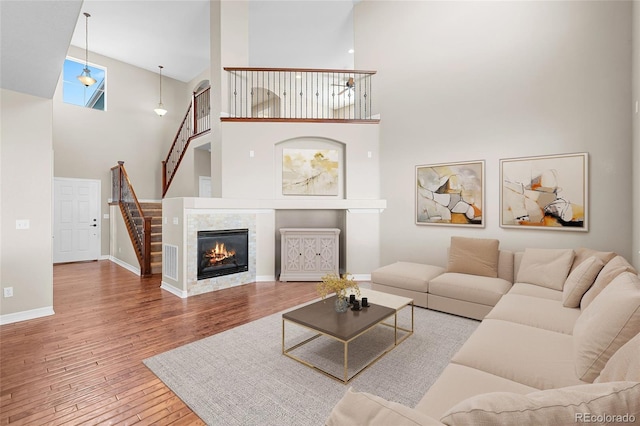 living area with visible vents, baseboards, a tiled fireplace, stairway, and wood finished floors