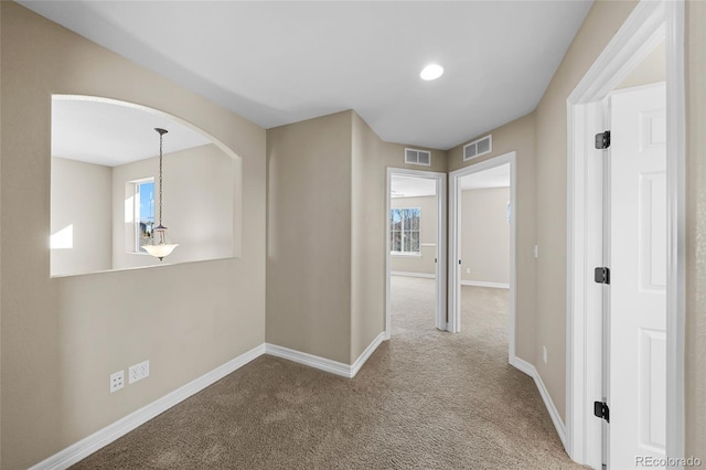 hallway featuring visible vents, carpet floors, and baseboards