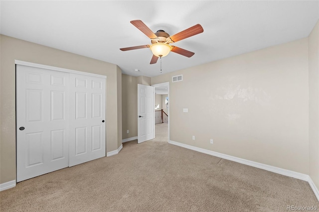 unfurnished bedroom featuring light colored carpet, visible vents, a closet, and baseboards