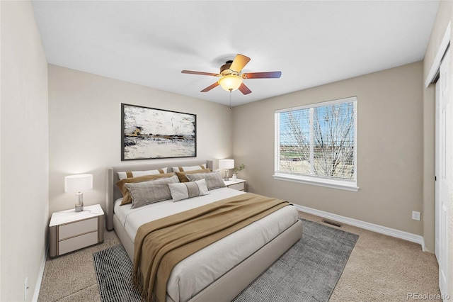 carpeted bedroom with visible vents, baseboards, and a ceiling fan