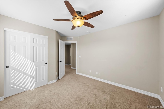 unfurnished bedroom featuring visible vents, baseboards, light carpet, a closet, and a ceiling fan