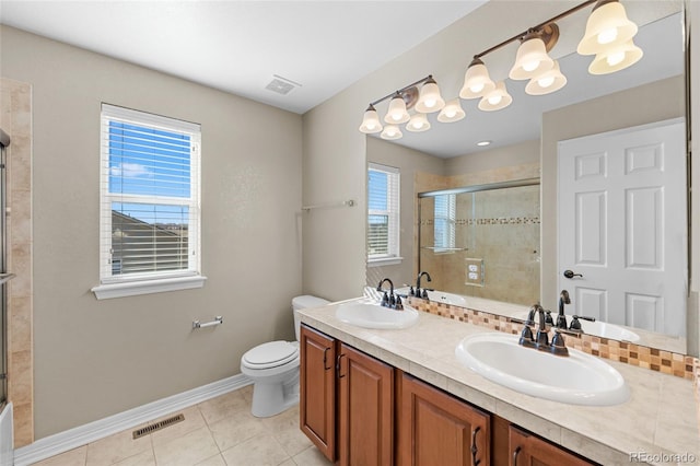 full bathroom with plenty of natural light, tiled shower, visible vents, and a sink