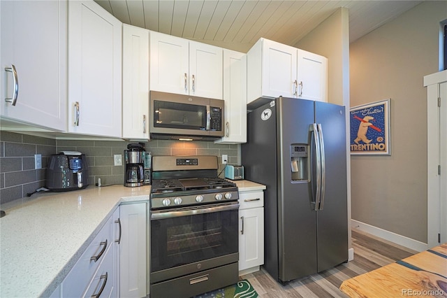 kitchen featuring appliances with stainless steel finishes, white cabinetry, backsplash, light stone counters, and light hardwood / wood-style floors