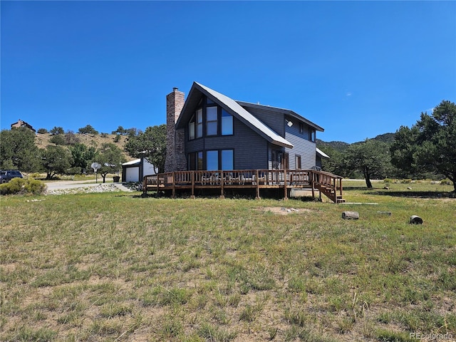 rear view of property featuring an outbuilding, a lawn, a deck, and a garage