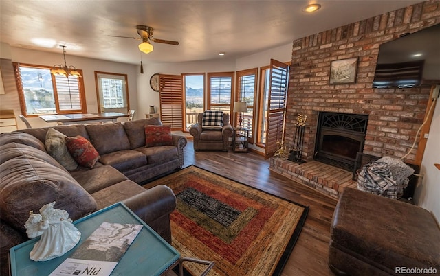 living room featuring a fireplace, hardwood / wood-style flooring, brick wall, and ceiling fan