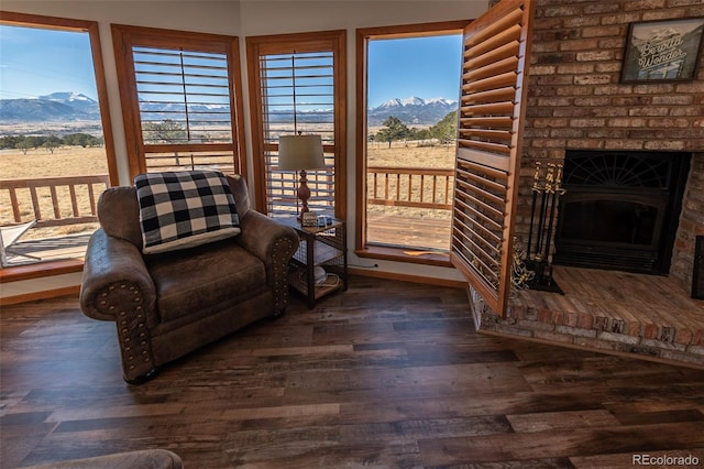 unfurnished room with a fireplace, dark hardwood / wood-style flooring, a mountain view, and brick wall