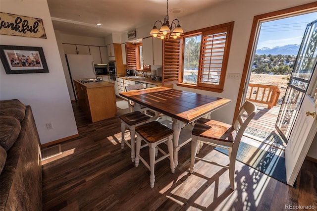 dining area with a mountain view, dark hardwood / wood-style floors, sink, and a chandelier