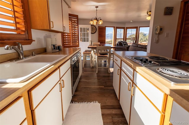 kitchen with decorative light fixtures, ceiling fan with notable chandelier, white cabinetry, sink, and dark hardwood / wood-style floors