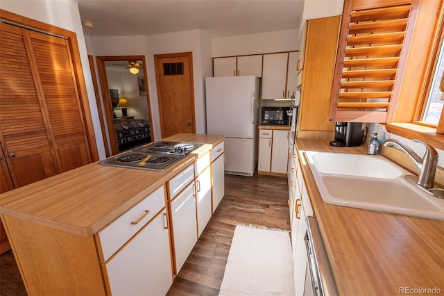 kitchen with white cabinetry, a center island, ceiling fan, white refrigerator, and light hardwood / wood-style floors