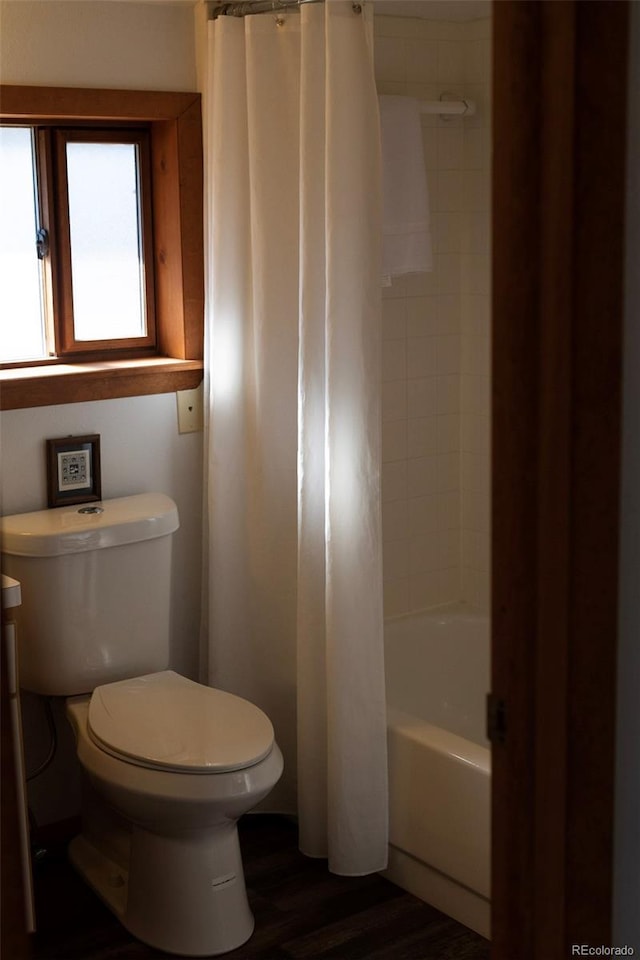 bathroom with wood-type flooring, toilet, and shower / bathtub combination with curtain