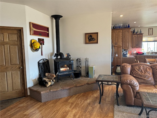 living room featuring hardwood / wood-style flooring, a wood stove, and sink