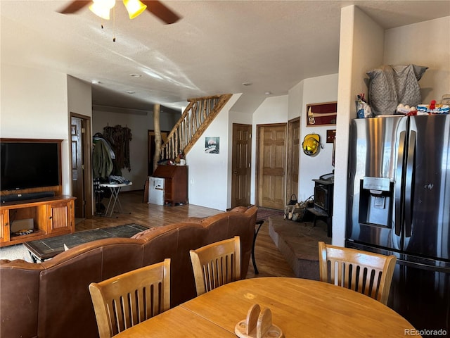 dining space with hardwood / wood-style flooring, ceiling fan, a wood stove, and a textured ceiling