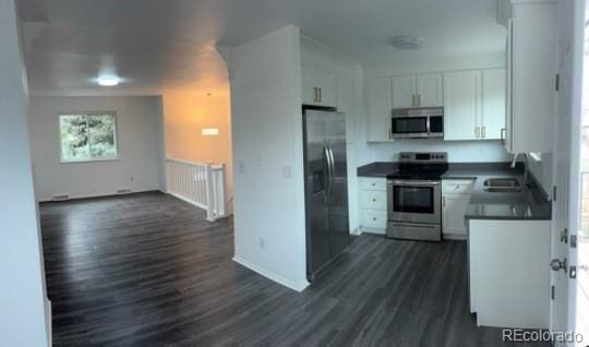 kitchen with dark wood-type flooring, a sink, white cabinetry, and stainless steel appliances