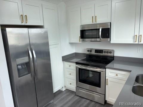 kitchen with dark wood finished floors, appliances with stainless steel finishes, and white cabinetry