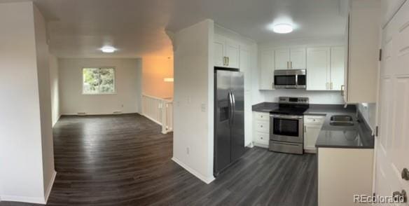 kitchen with dark wood-style flooring, dark countertops, appliances with stainless steel finishes, and white cabinetry