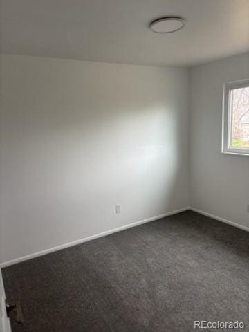 unfurnished room featuring baseboards and dark colored carpet