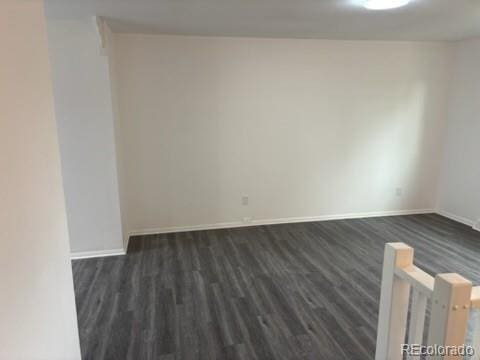 spare room featuring baseboards and dark wood-style floors