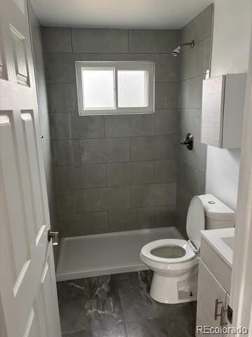 full bath featuring vanity, a tile shower, toilet, and marble finish floor