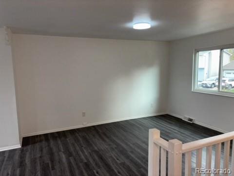 unfurnished room with dark wood-style flooring, baseboards, and visible vents